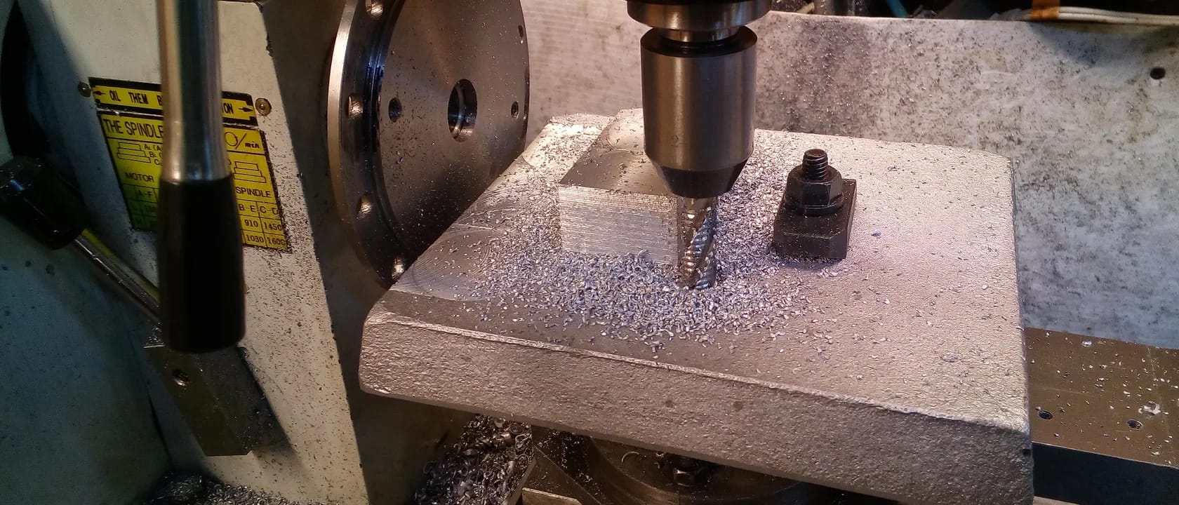 Schruppfräser beim Bearbeiten eines gespannten Aluminiumwerkstücks, mit Spänen um das Werkzeug.